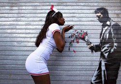 A dancer poses with a new installation of art by British graffiti artist Banksy painted on the front door of the Hustler Club in New York October 24, 2013. Known for his anti-authoritarian black-and-white stenciled images, which have sold at auction for upwards of $2 million, the British street artist is treating New Yorkers to a daily dose of spray-painted art - while eluding the police and incurring the wrath of New York Mayor Michael Bloomberg. REUTERS/Eric Thayer (UNITED STATES - Tags: SOCIETY TPX IMAGES OF THE DAY)